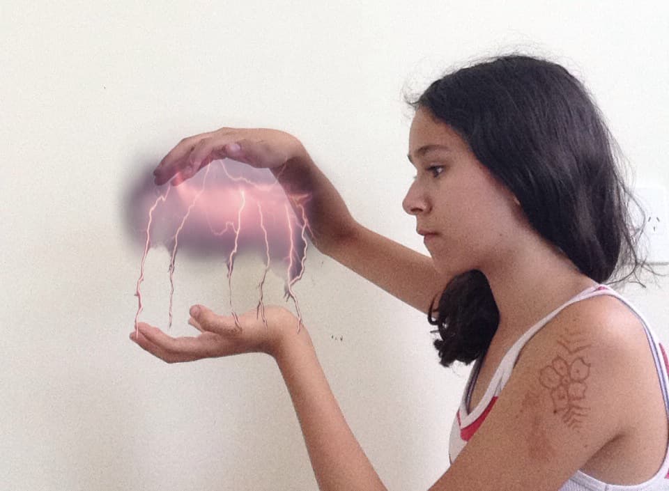 poorly edited photo of me looking towards my separated hands holding a lightning storm between them